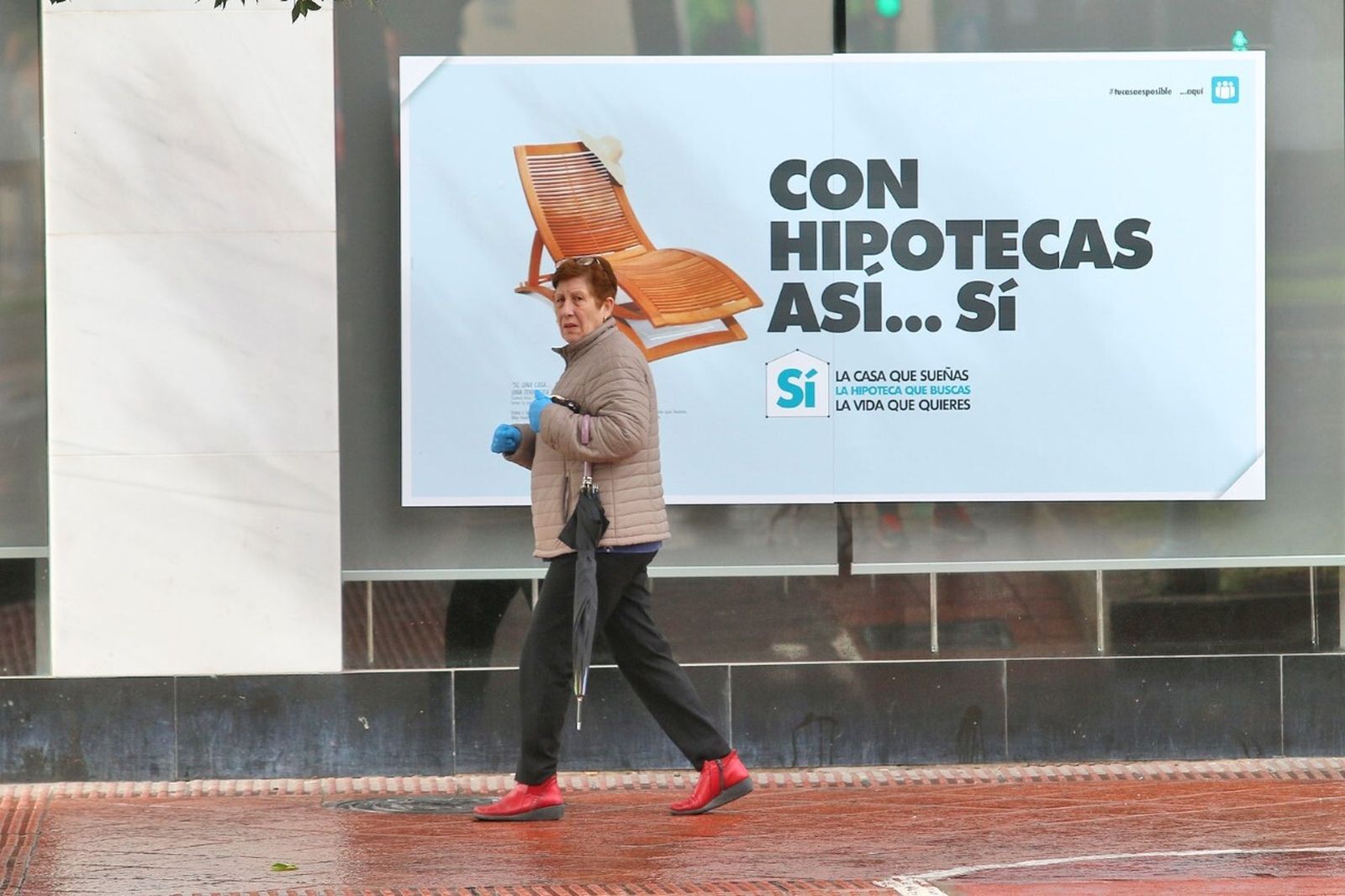 Una mujer pasa delante de la publicidad de una hipoteca.