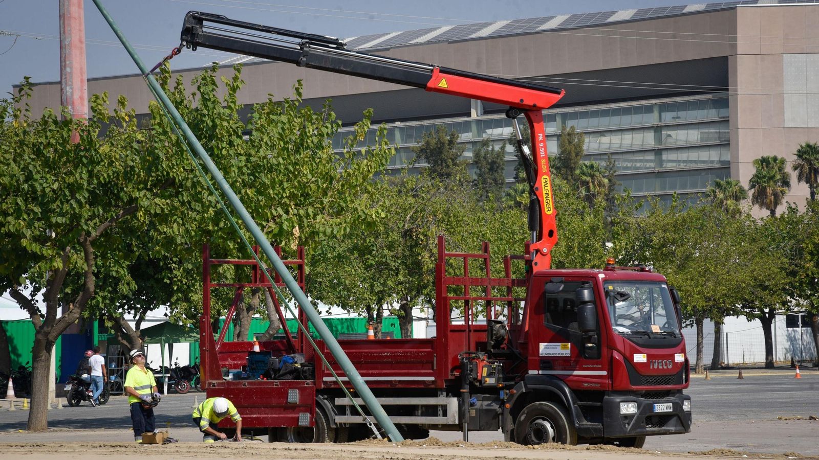 Operarios del servicio de Alumbrado Público colocan una de las columnas que iluminarán el parking de motos, ayer.