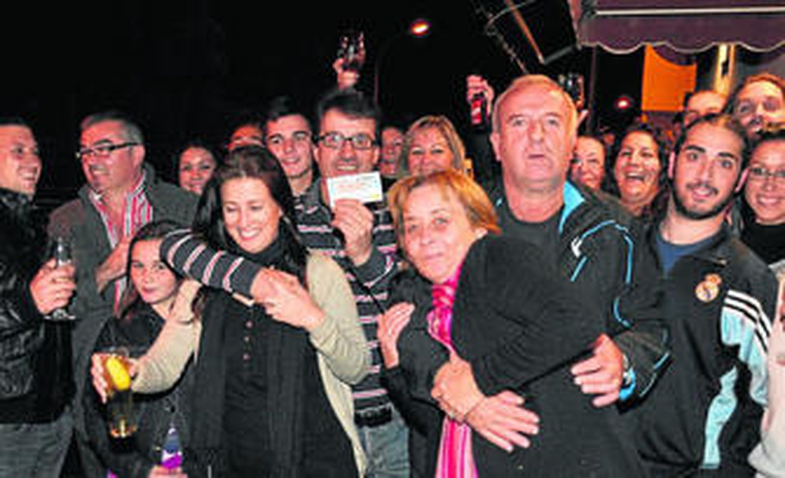 Agustín Bermudo, a la derecha con barba y chándal del Madrid, festeja con agraciados la suerte en la calle Bernarda Alba de La Rinconada.