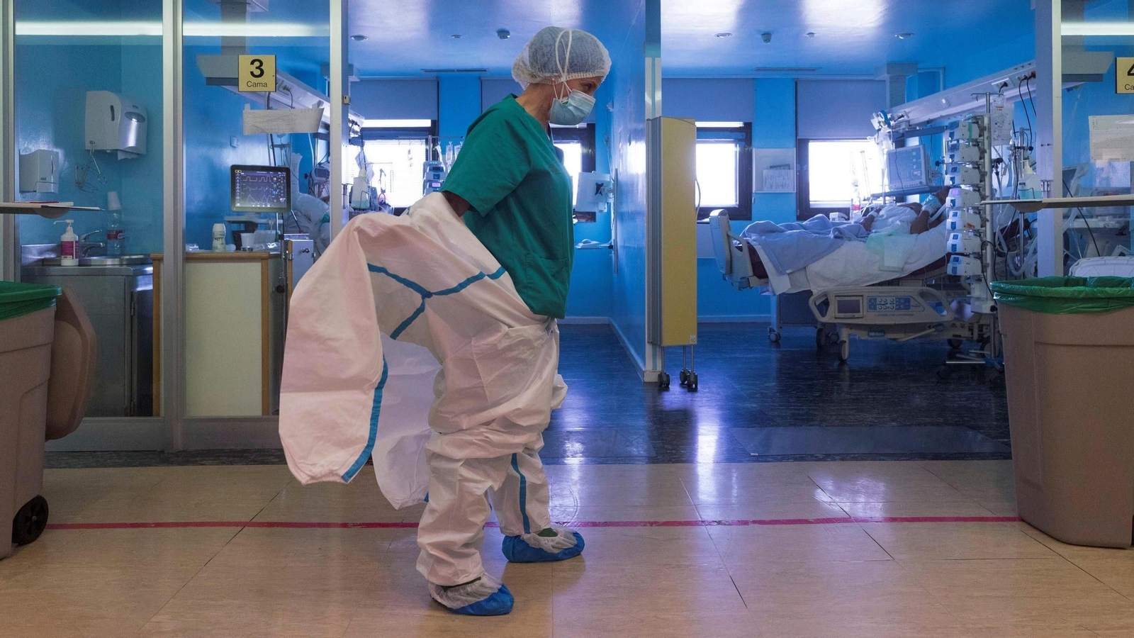 Una sanitaria  se coloca un EPI  antes den entrar en uno de los boxes de la UCI.