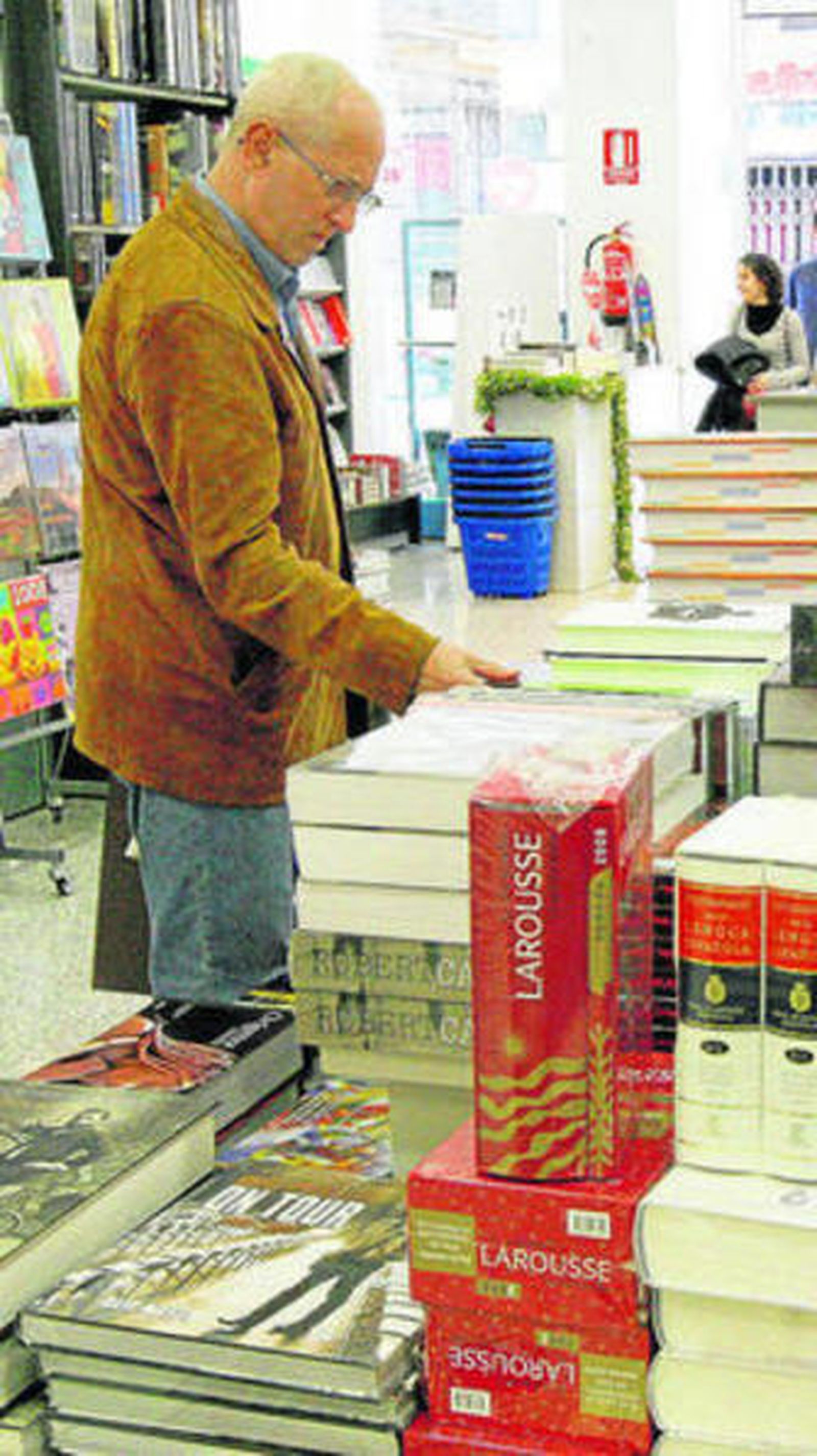 Un hombre busca libros en una estantería.