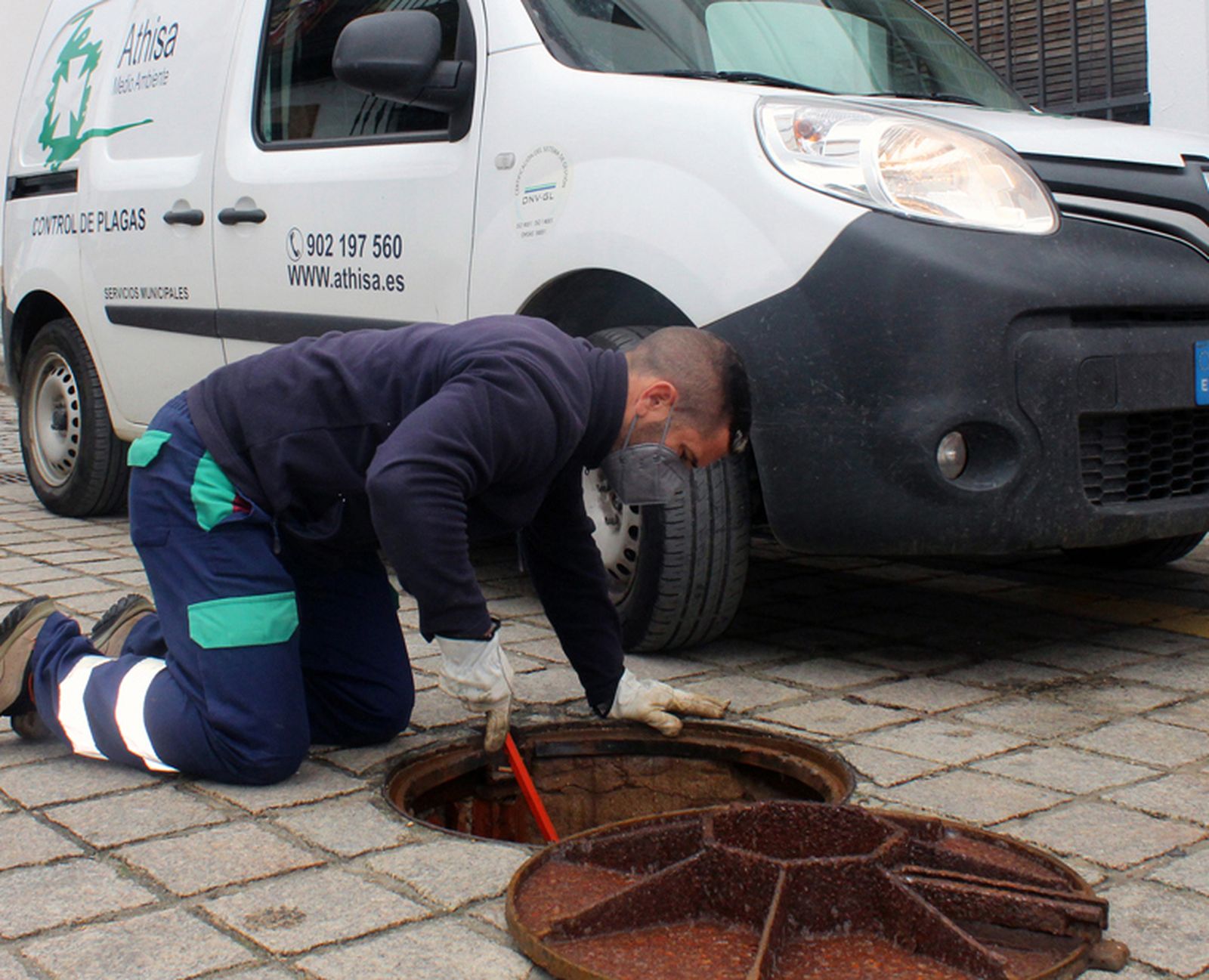 Un trabajador del Ayuntamiento fumiga en una alcantarilla