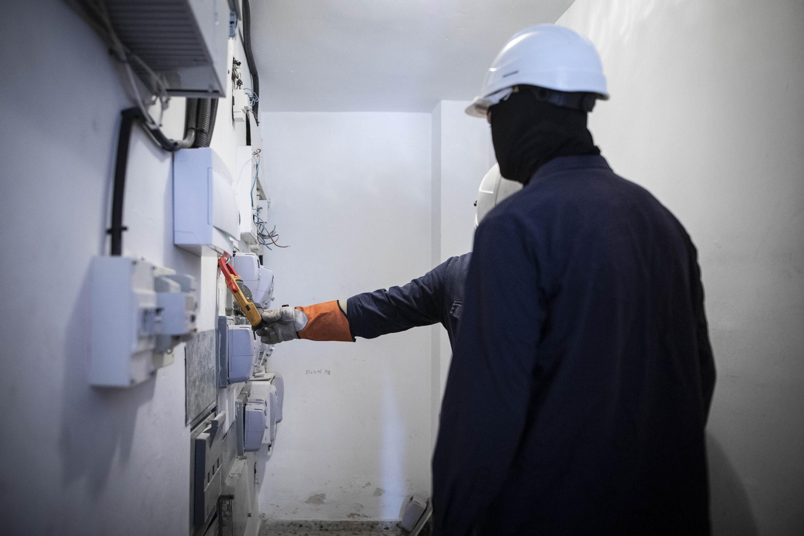 Dos técnicos de Endesa actúan ante un enganche ilegal en el distrito.