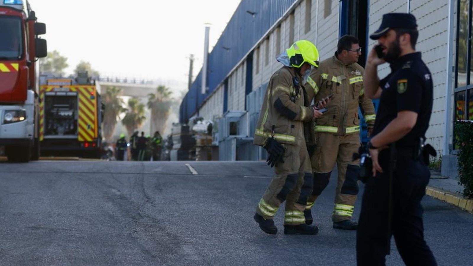Bomberos y policías en la fábrica incendiada.