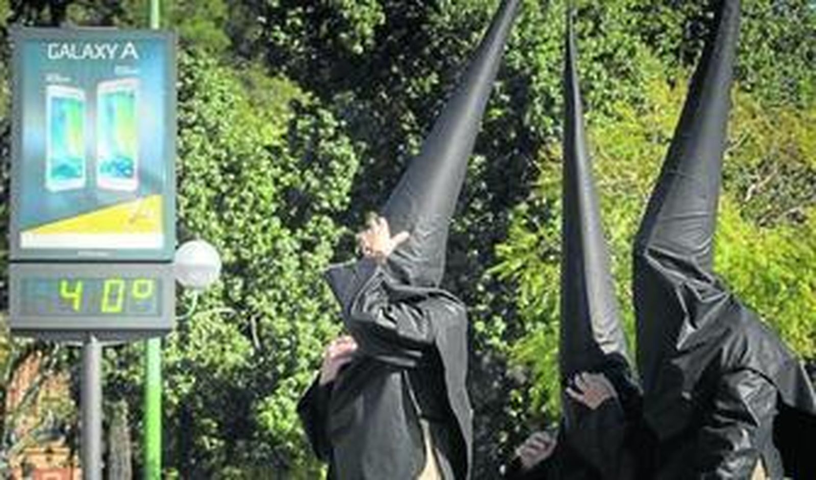 Nazarenos de Santa Cruz pasan ante un termómetro que marca 40 grados.