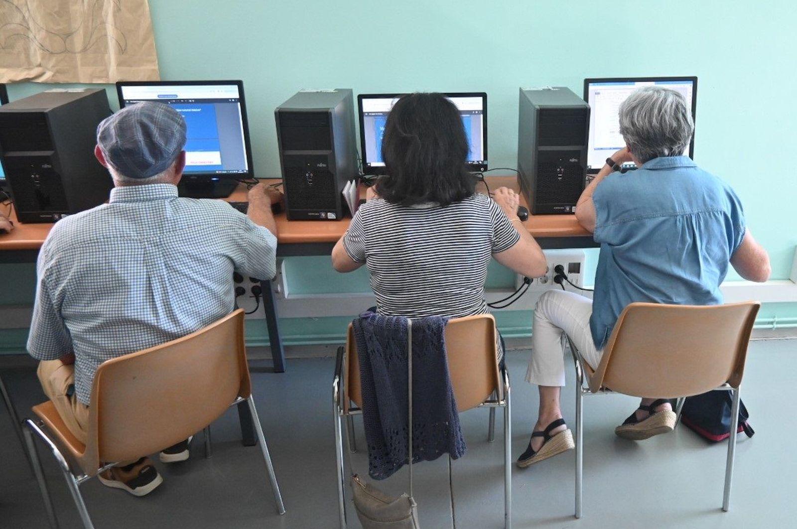 Varias personas mayores utilizan ordenadores para navegar por la red.