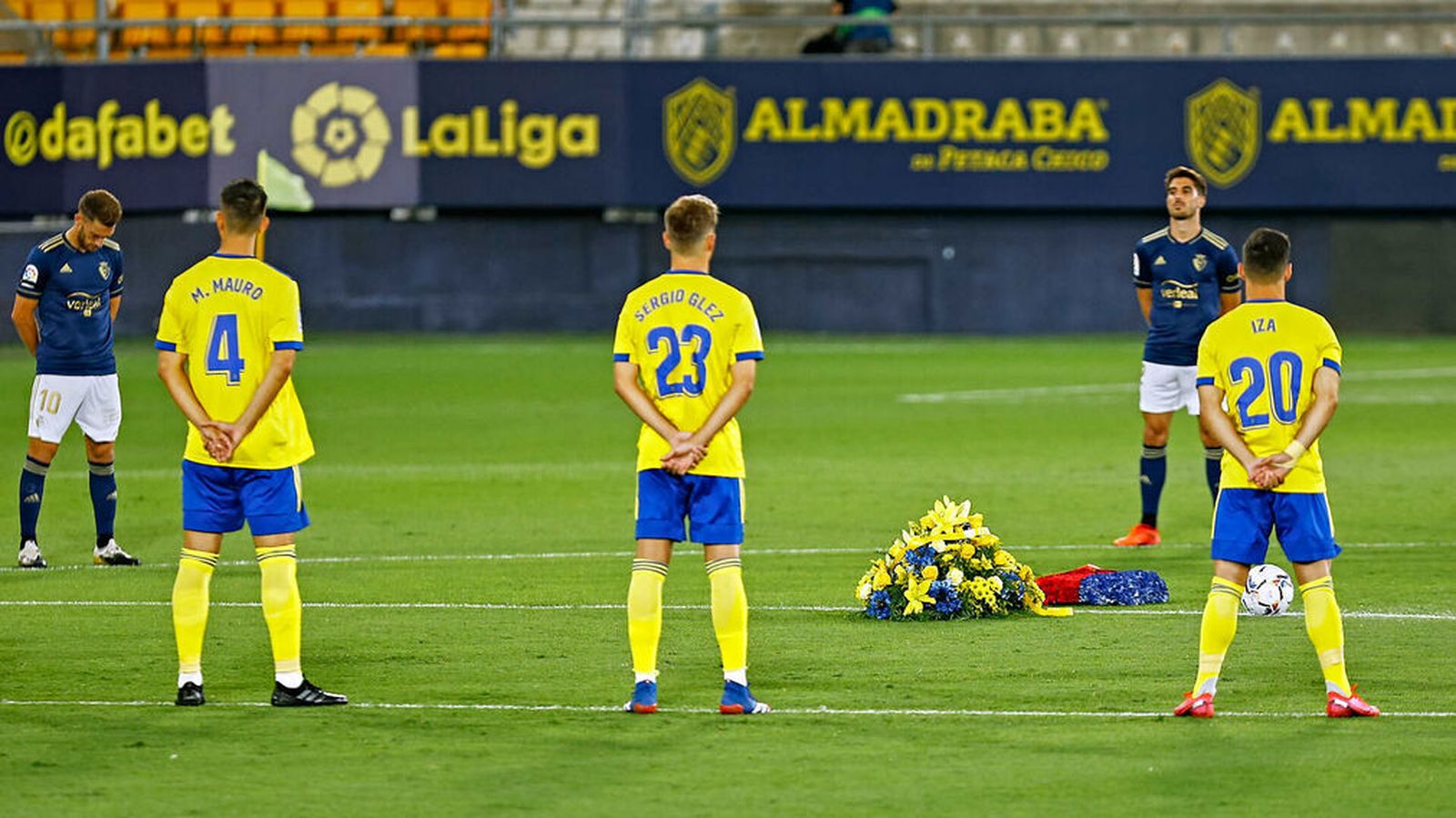 Minuto de silencio con ramos de flores sobre el césped.
