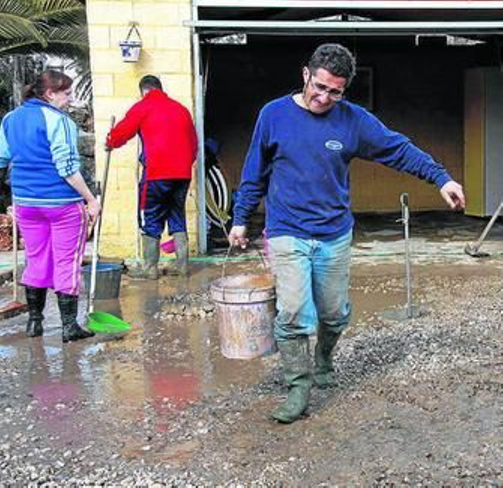 Vecinos limpian el interior de una vivienda anegada de agua.