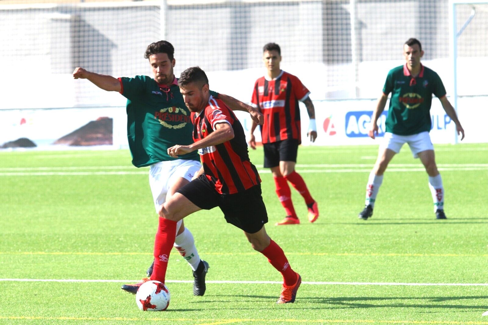 Un jugador pulpileño conduce el esférico ante la presión de un rival.