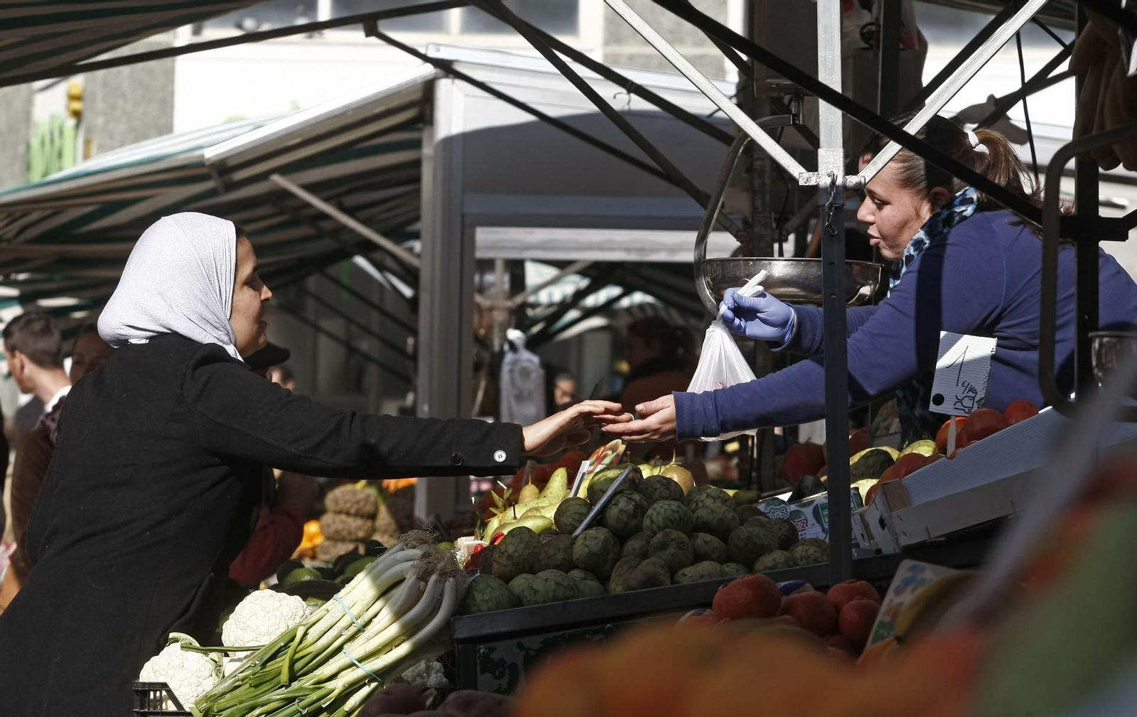 Una mulsuma cubierta con hiyab compra en uno de los puestos del mercado Algeciras.