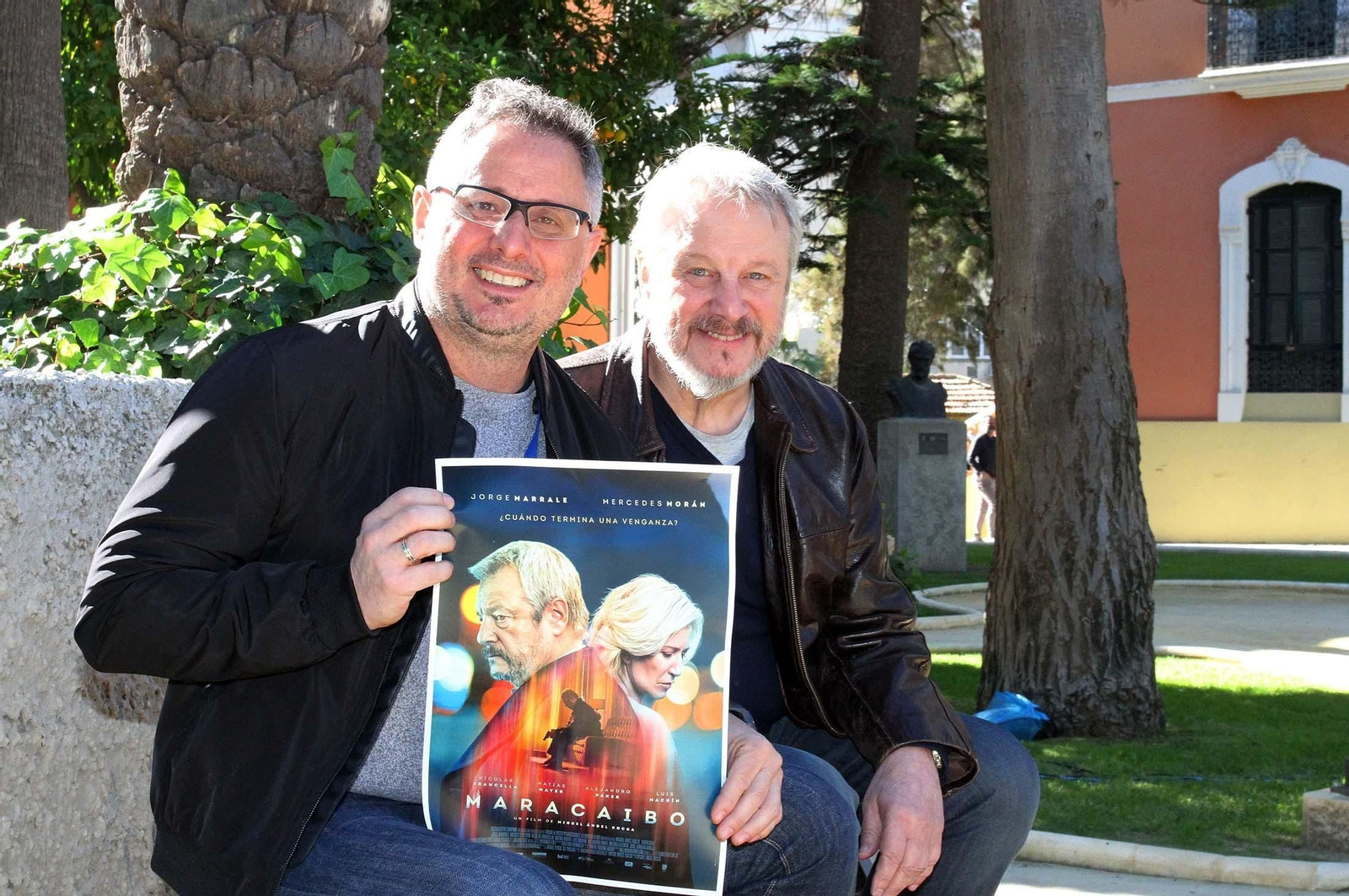 El director, Miguel Ángel Rocca, posa con el cartel de la película acompañado por el actor Jorge Marrale.