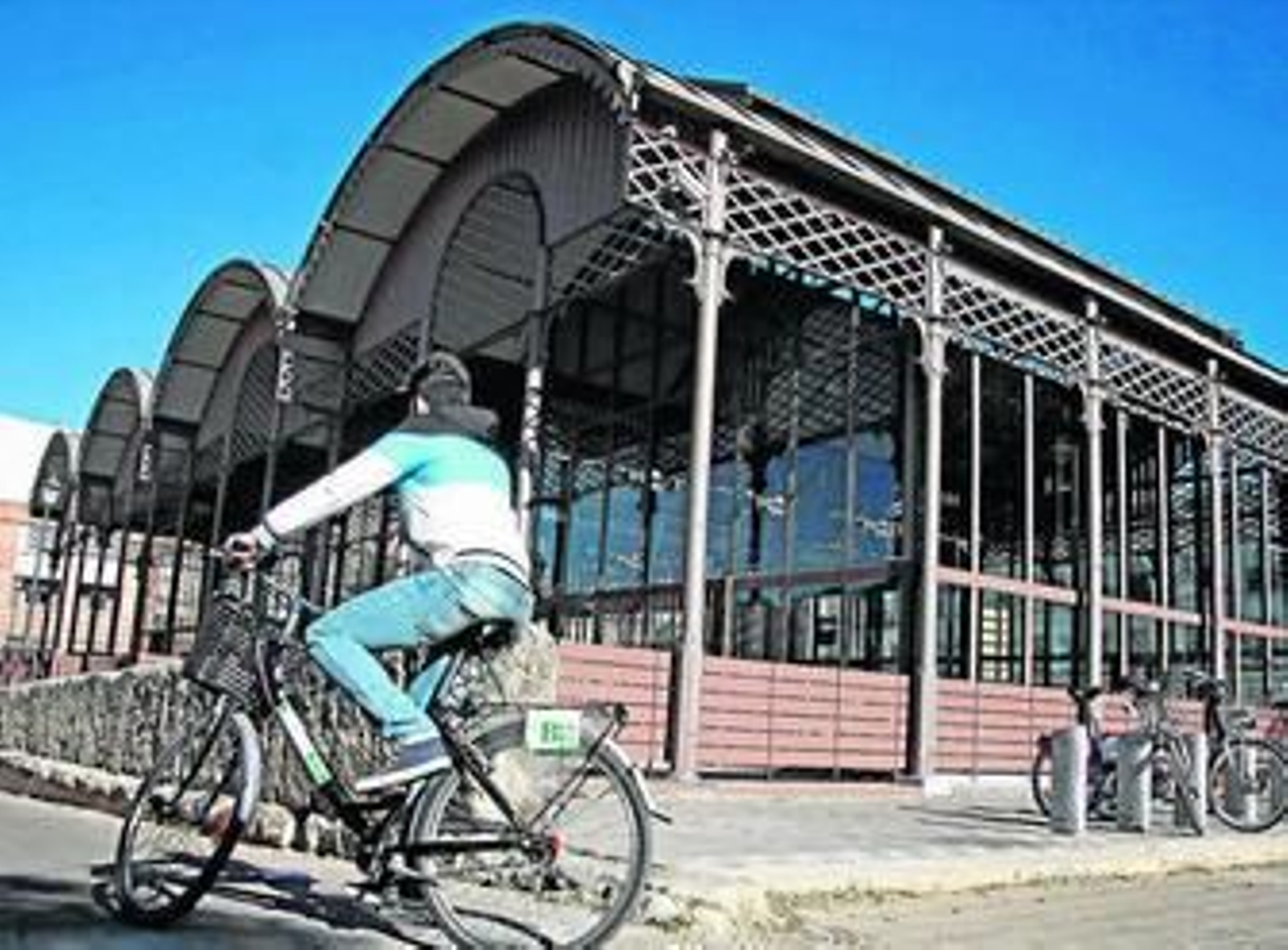 Un ciclista pasa junto a las Naves del Barranco, junto al Puente de Triana.