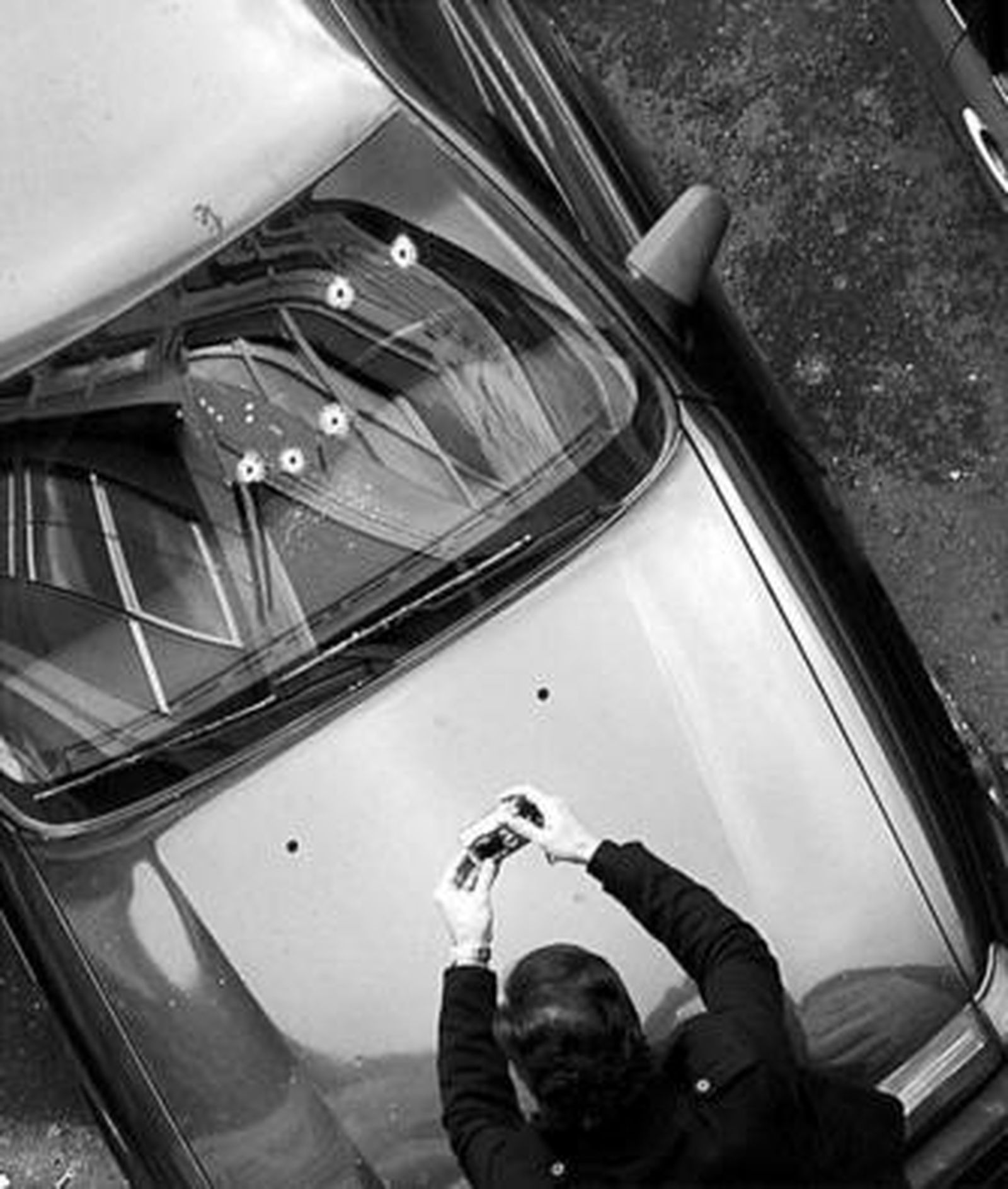 Un miembro de la Ertzaintza toma fotografías de los impactos en el coche de Carrasco.