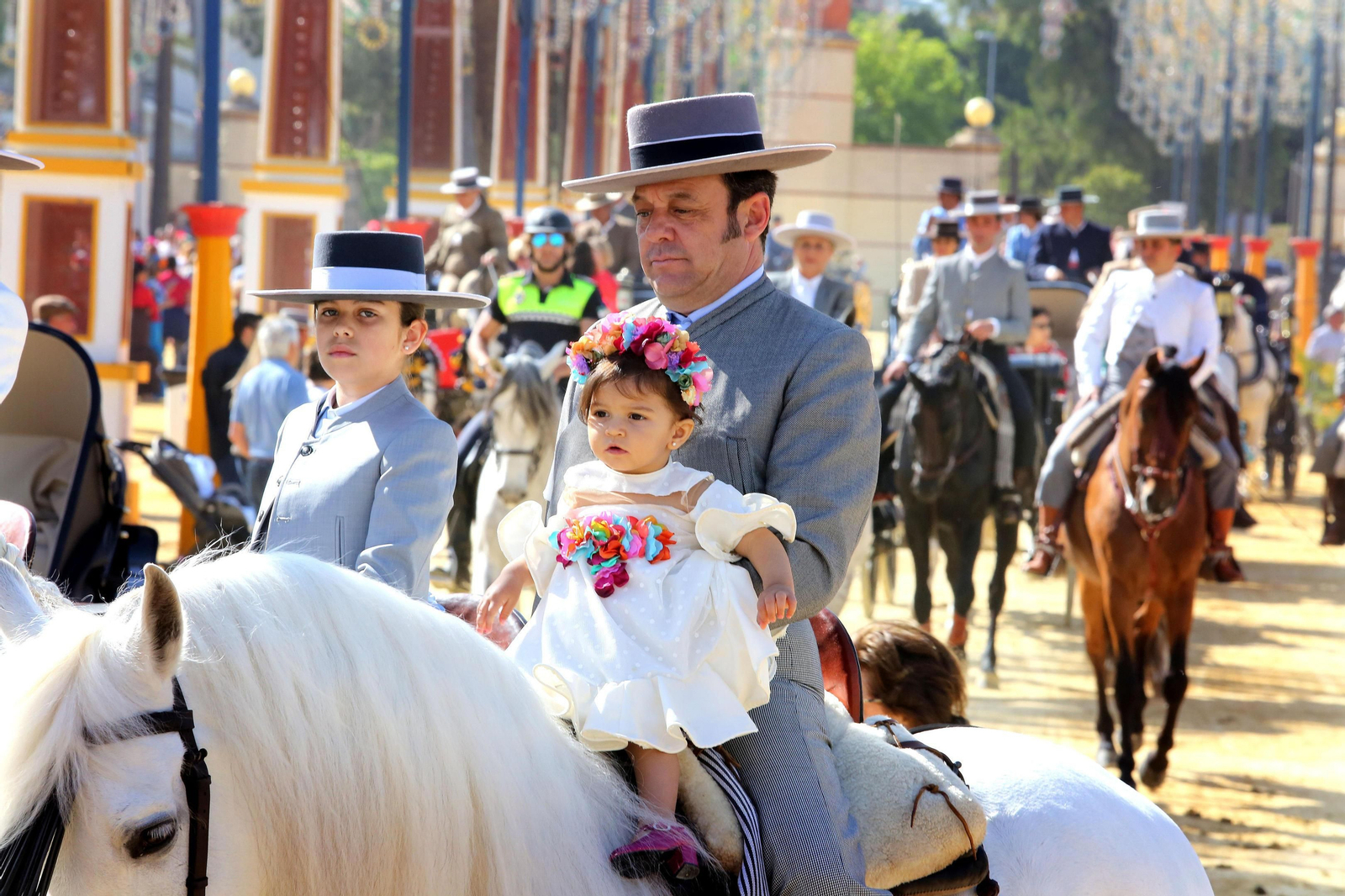 Una niña vestida de flamenca, a caballo.