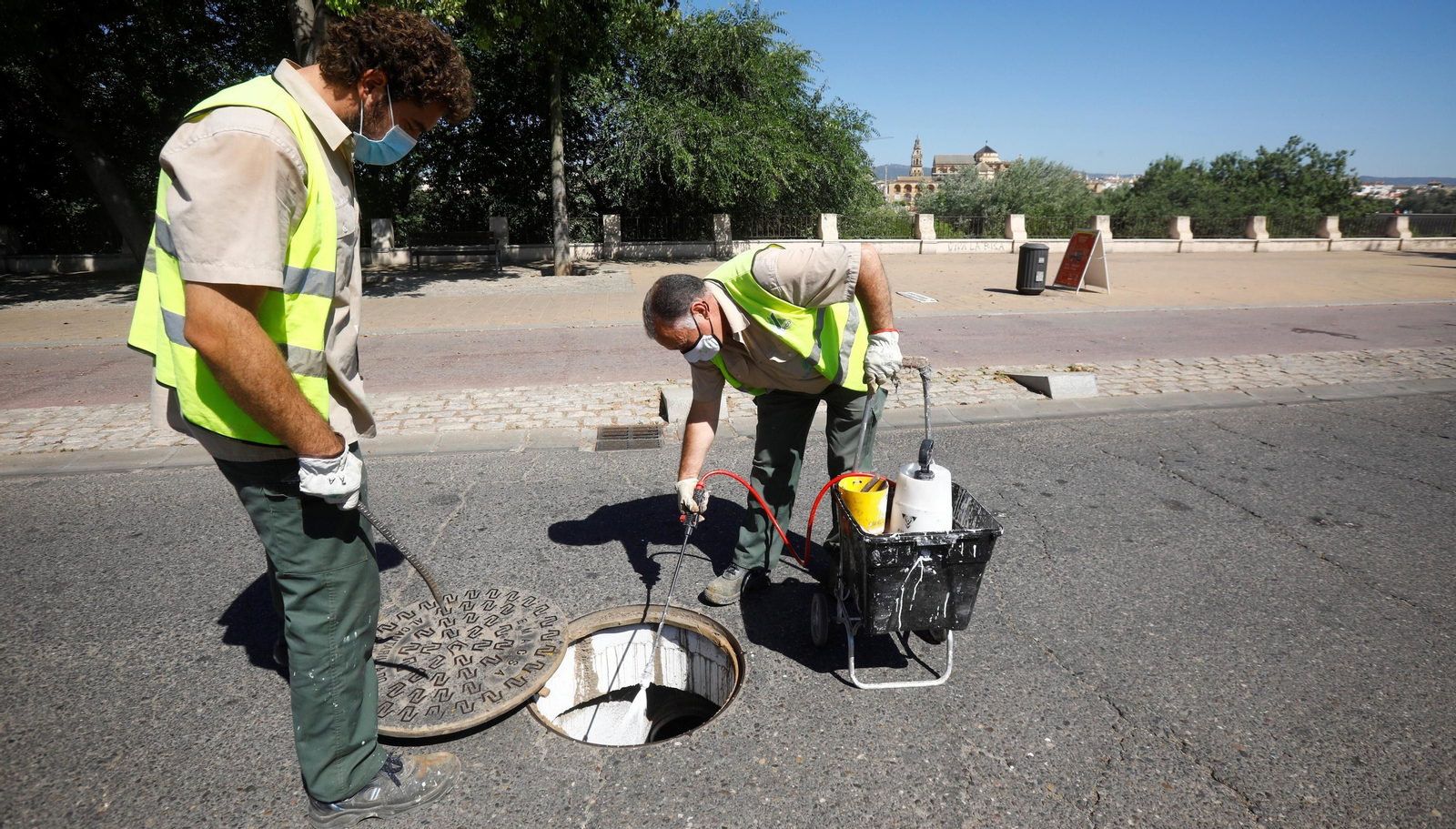 Dos trabajadores de Control de Plagas de Sadeco realizan un tratamiento en una alcantarilla.