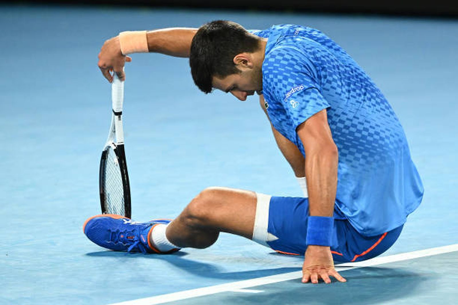 Djokovic en el suelo donde se le aprecia el aparatoso vendaje en su pierna izquierda.