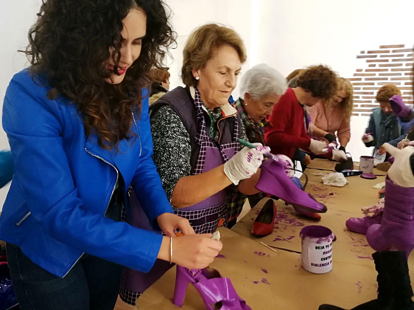 Mujeres pintando zapatos en color morado, que serán recogidos en la plaza de la Concordia