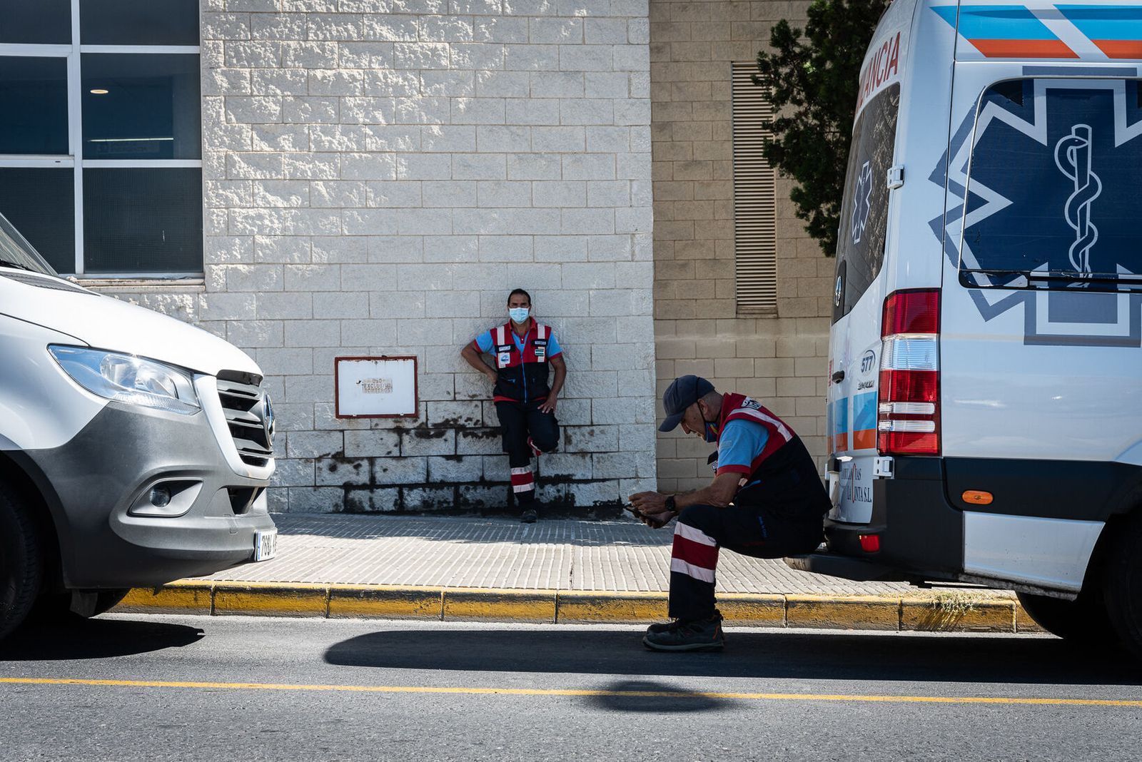 Dos sanitarios descansan junto a una ambulancia en las inmediaciones del Hospital Juan Ramón Jiménez de la capital onubense.