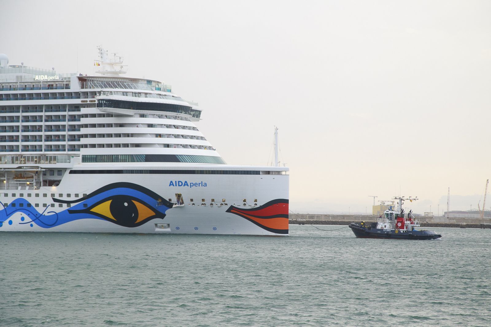 Un remolcador ayuda al Aida Perla a atracar.