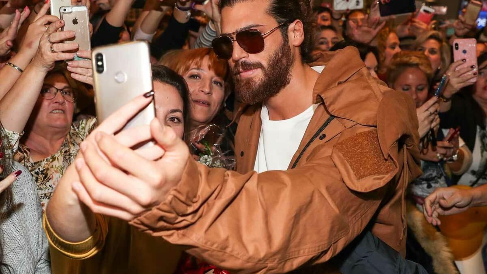 Can Yaman se hace fotos con sus fans a su llegada al aeropuerto de Madrid.