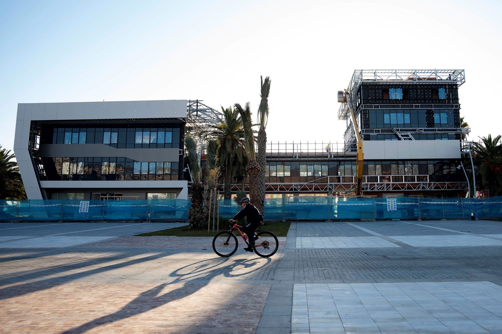 Un ciclista recorre los nuevos espacios portuarios ganados por la ciudad con el edificio de la Autoridad Portuaria en obras.