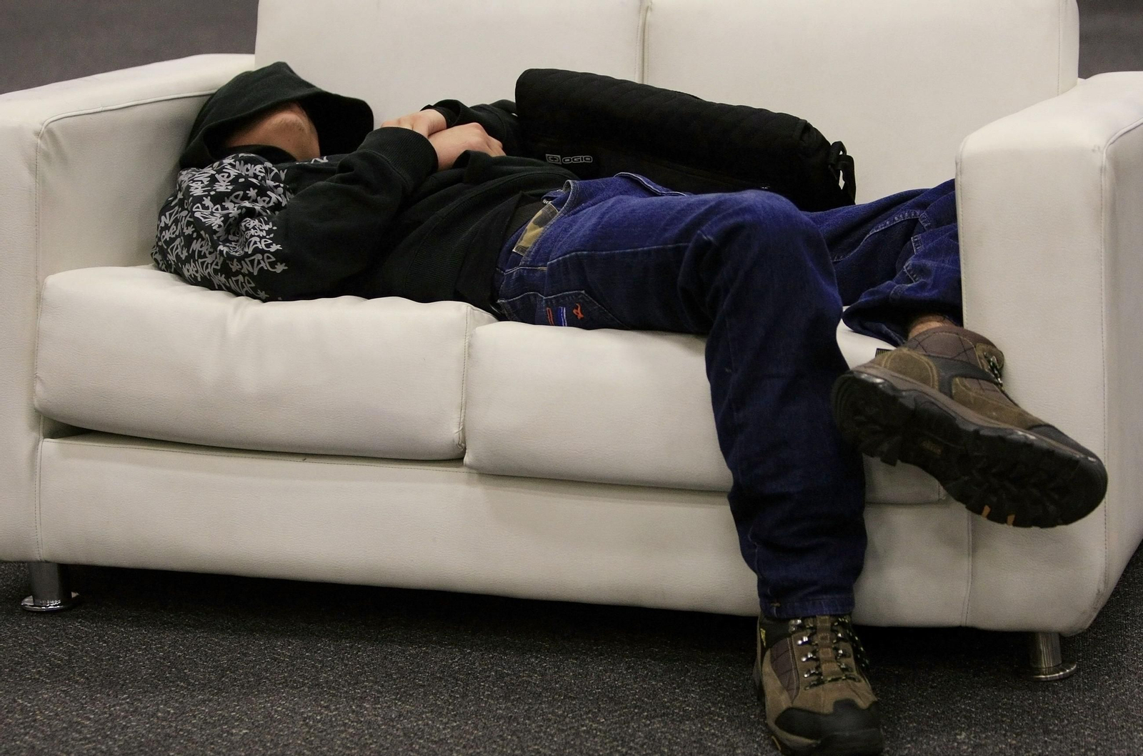 Una persona acostada en un sofá intentando dormir para descansar.