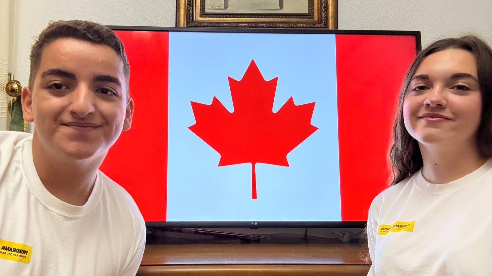 Javier y María posan junto a la bandera de Canadá, su próximo destino.