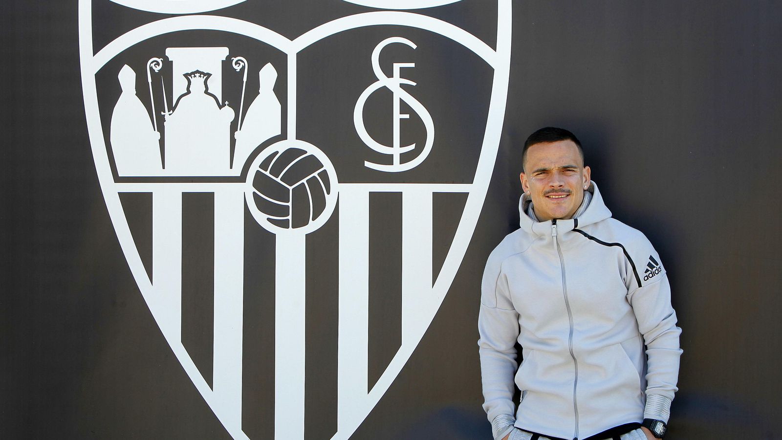 Roque Mesa, ante un escudo del Sevilla.