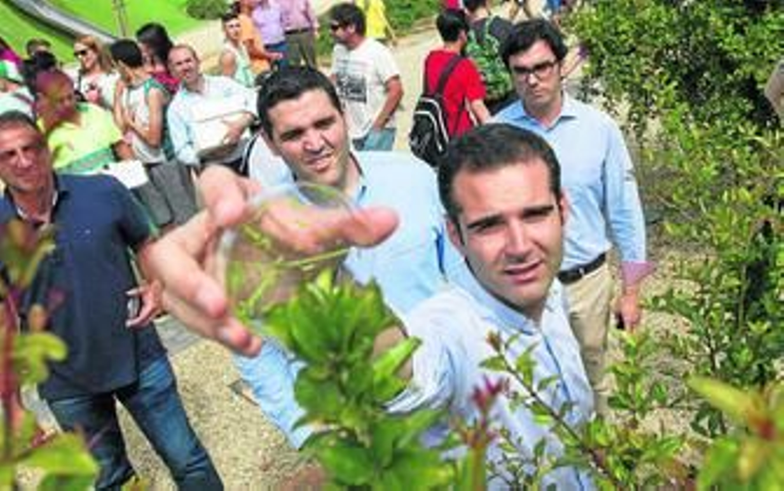 El alcalde suelta insectos 'buenos' sobre plantas arbustivas del parque de Las Familias, mientras que el concejal de Medio Ambiente le mira con atención.