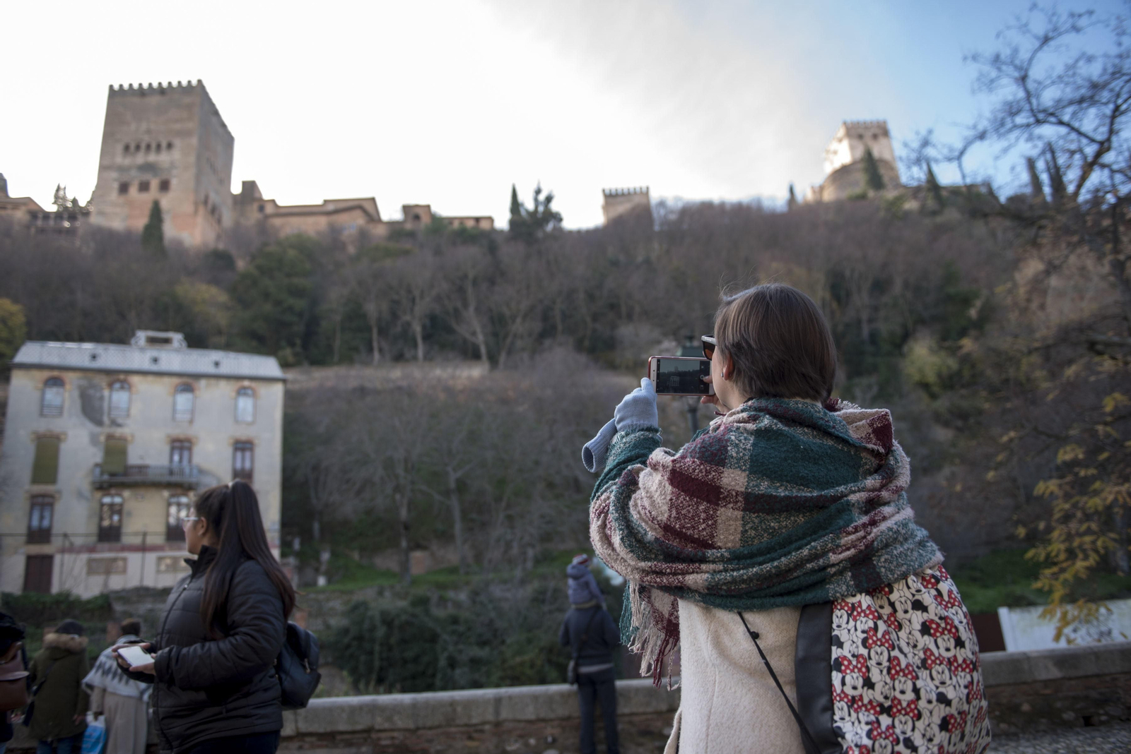 Una joven realiza una foto a la Alhambra desde el Paseo de los Tristes.