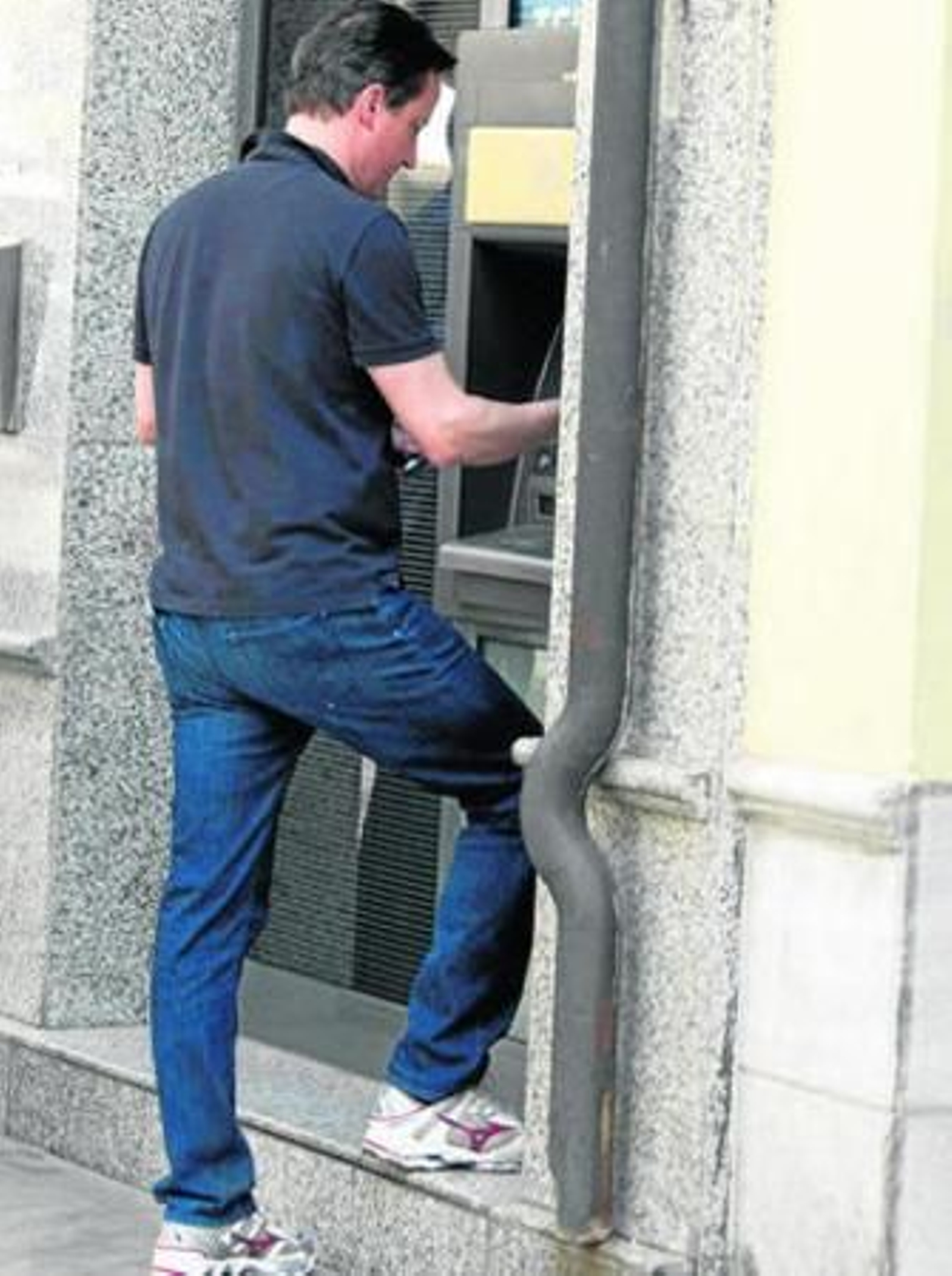 David Cameron saca dinero de un cajero.