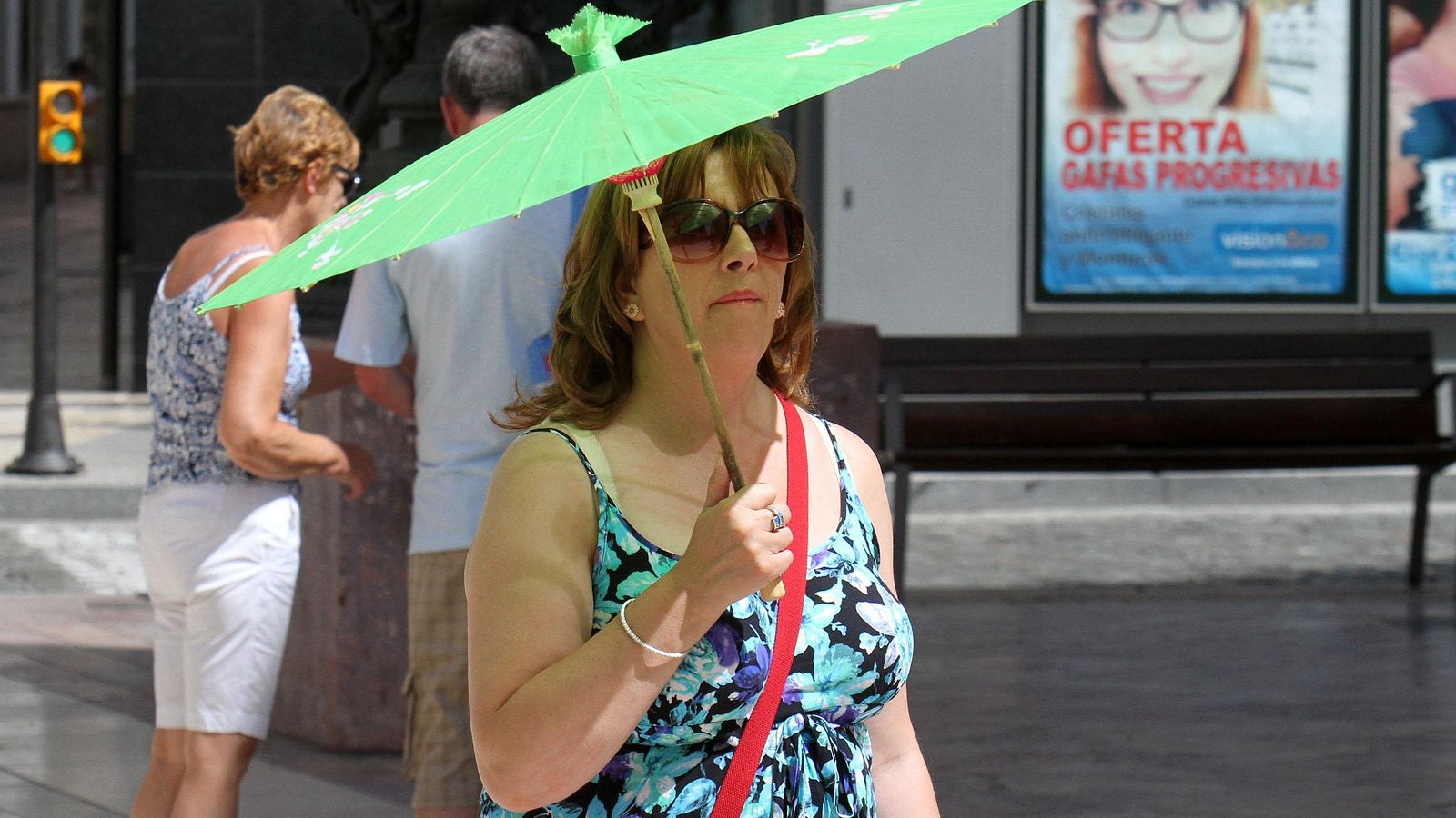 Una mujer pasea por als calles de Huelva con una sombrilla para protegerse del sol.