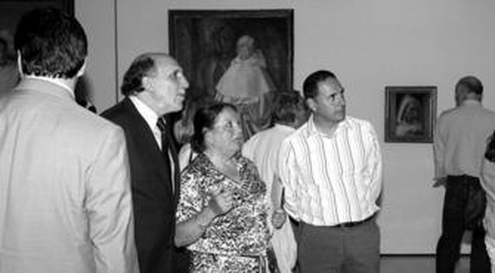 1. Juan José Oña y Manuel Ortega con la sobrina de Daniel Vázquez Díaz, Celia Vázquez. 2. Manuel Calvarro y Juan Manuel Seisdedos admirando el retrato de Hernán Cortés . 3. Cartel de la exposición a la entrada de la sala que albergan las veinticuatro obras. 4. Las pinturas despertaron la admiración de las personas que acudieron a la inauguración. 5. Un joven ante el cuadro 'La muerte del torero'.