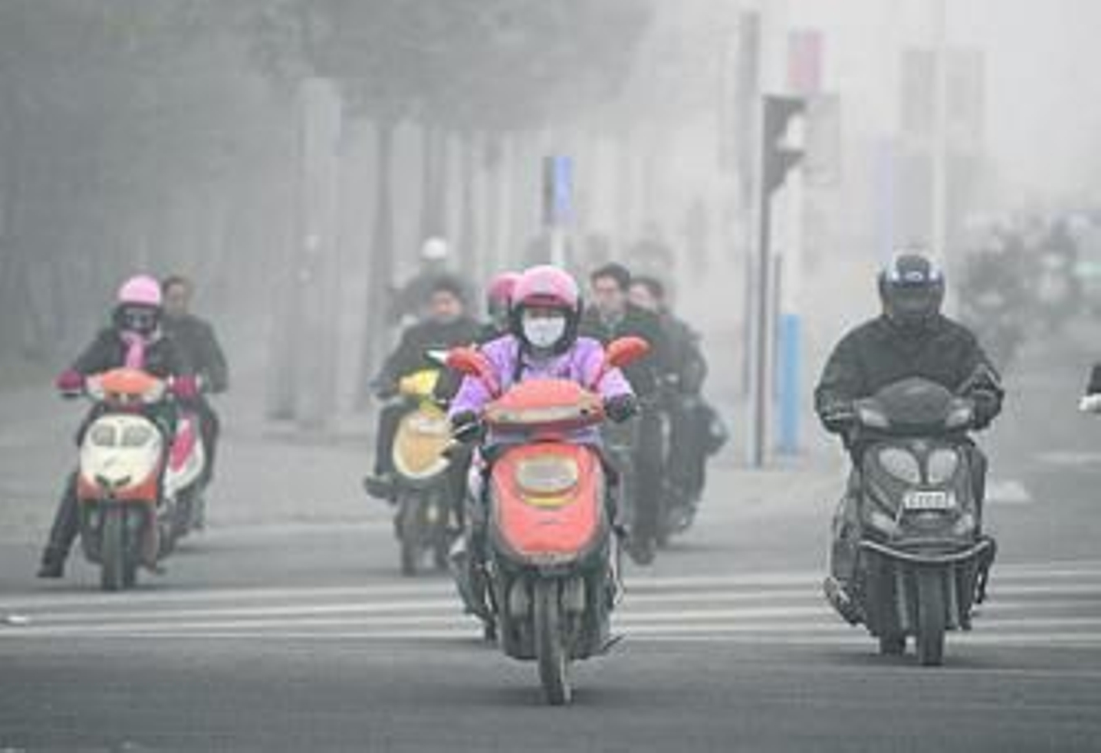Motoristas chinos circulan con un ambiente contaminado.