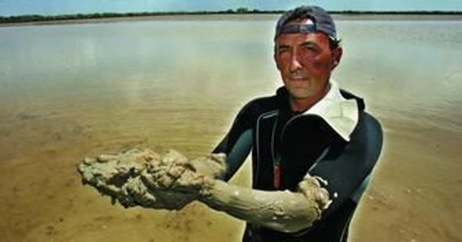 Un trabajador de la empresa acuícola de Trebujena muestra el barro acumulado en uno de los corrales.