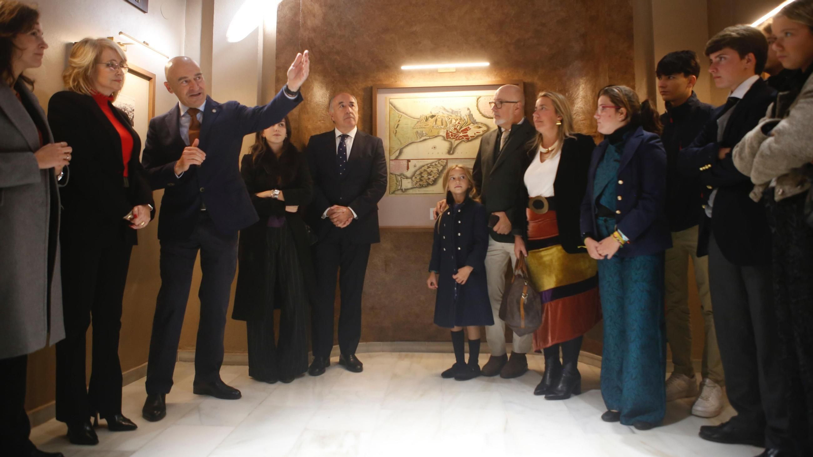 Los familiares de Viñas de Roa y autoridades municipales escuchan la explicación del historiador Ángel Sáez sobre el proceso de musealización de la capilla del Cristo de la Alameda.