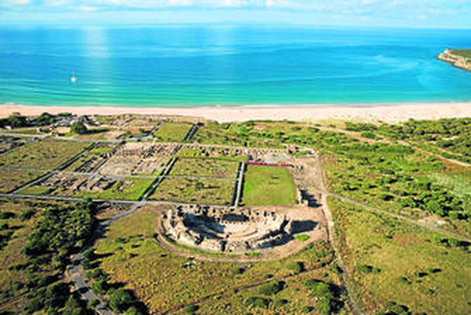 El complejo arqueológico de Baelo Claudia, en una imagen aérea en la que también se divisa la playa de Bolonia.