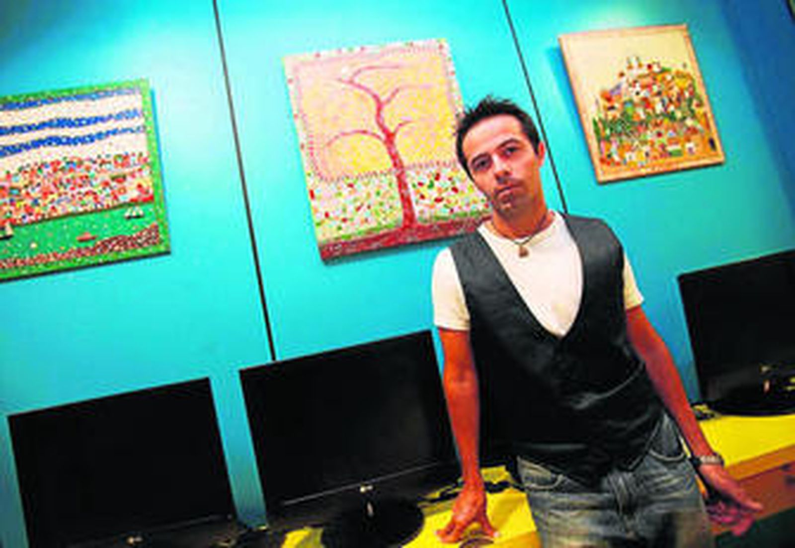 David Brenes, con varios de sus cuadros en la ludoteca de 'Activa Club', donde trabaja.