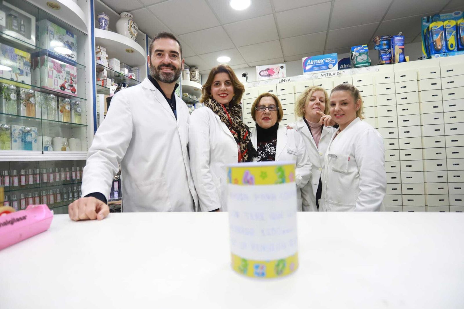 La plantilla de la Farmacia Ruiz Infante junto a la hucha solidaria para Teresa García, este martes.