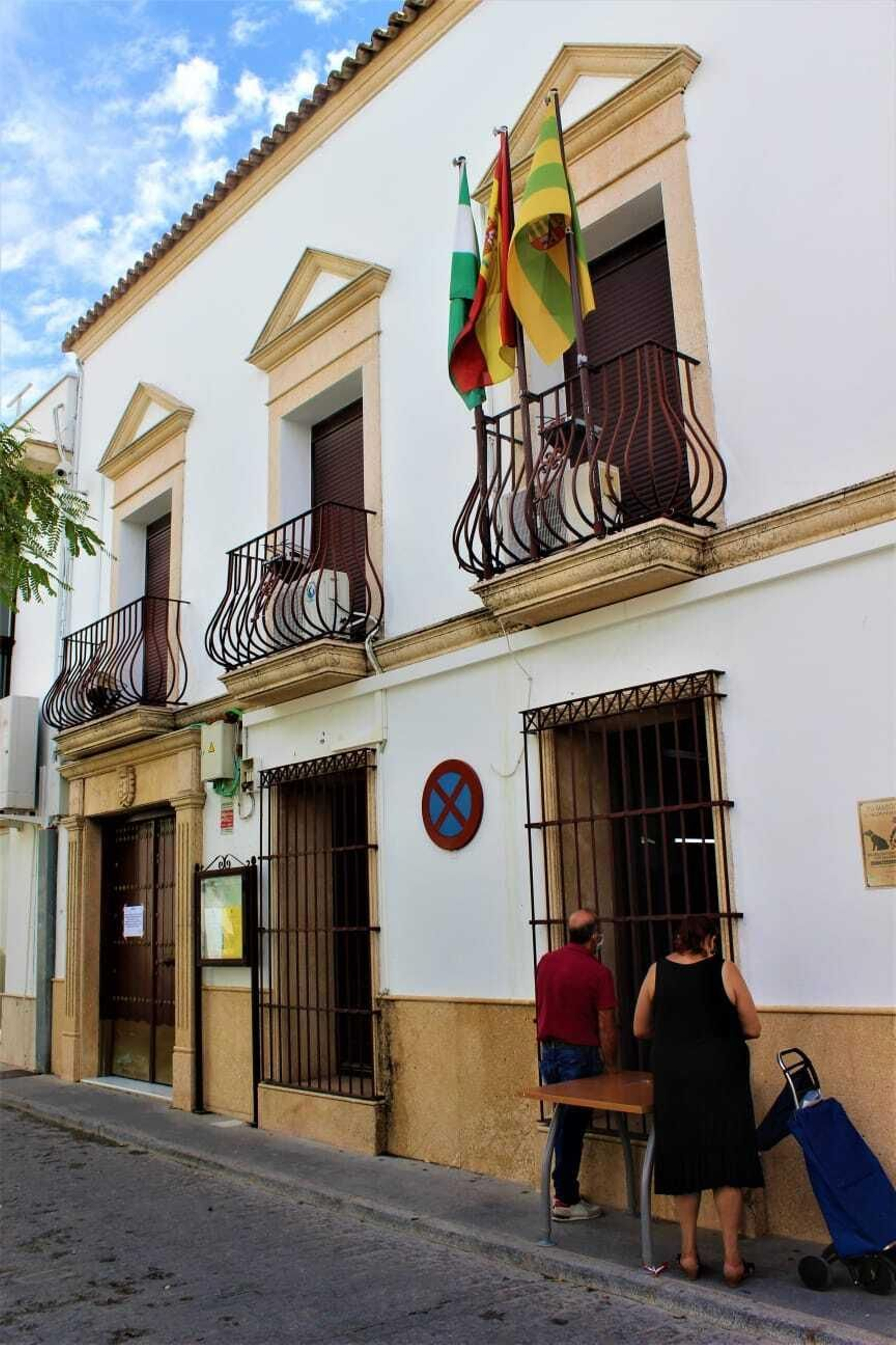 Dos vecinos son atendidos por una ventana del Ayuntamiento.