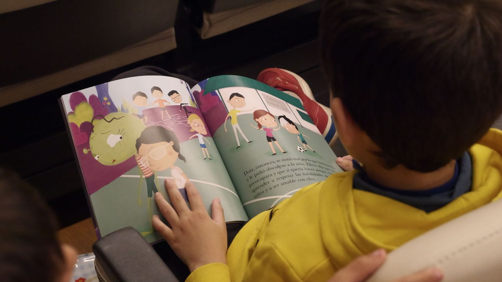 Un menor lee un libro ilustrado.