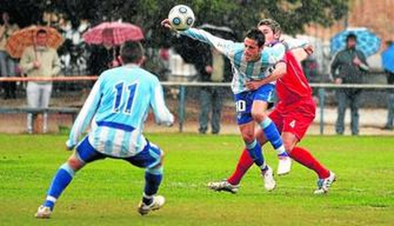 Un defensa del Adra agarra al malaguista Javi López ante la mirada de Portillo.