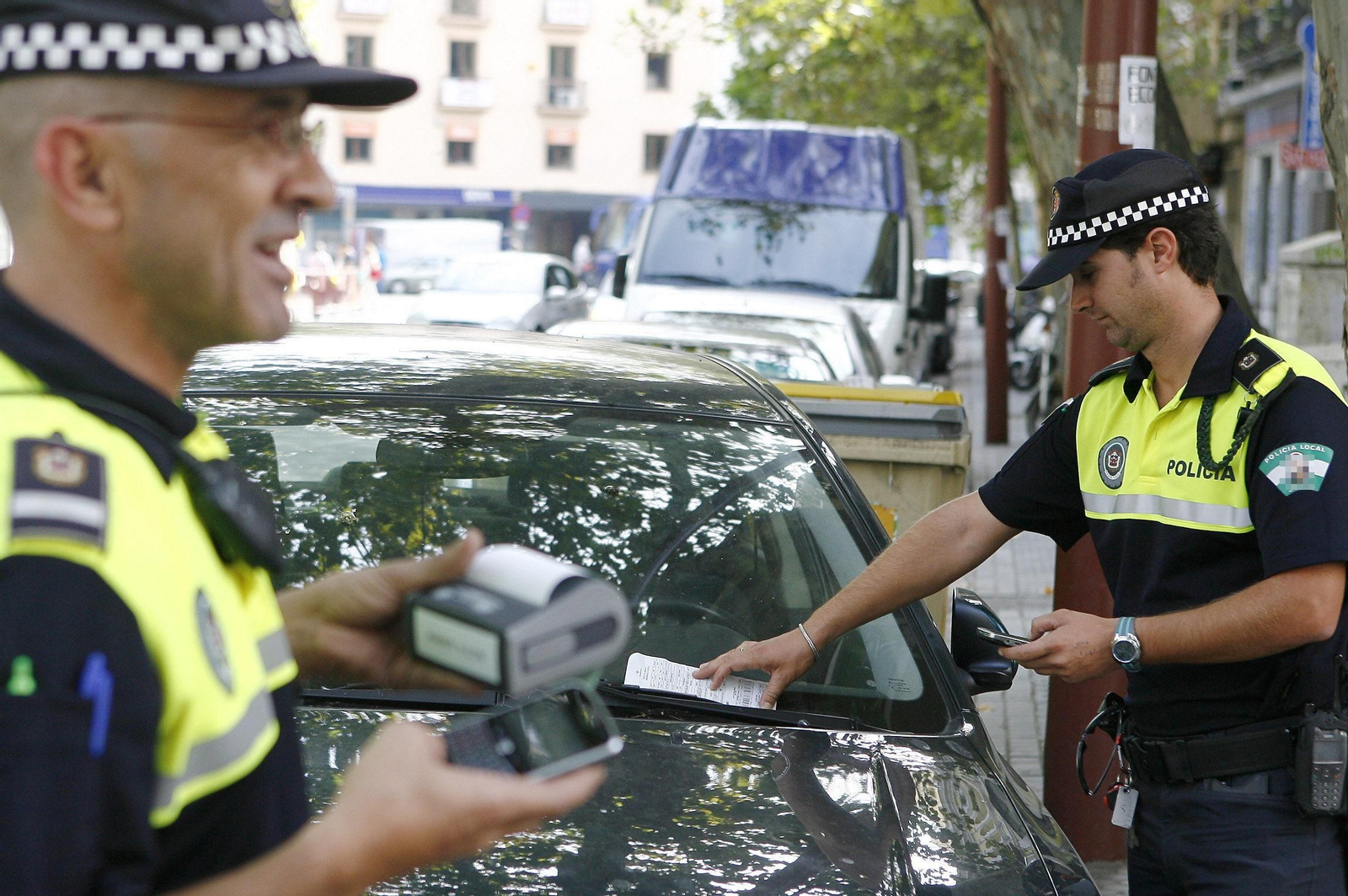 Dos agentes de Policía Local sancionando a vehículos