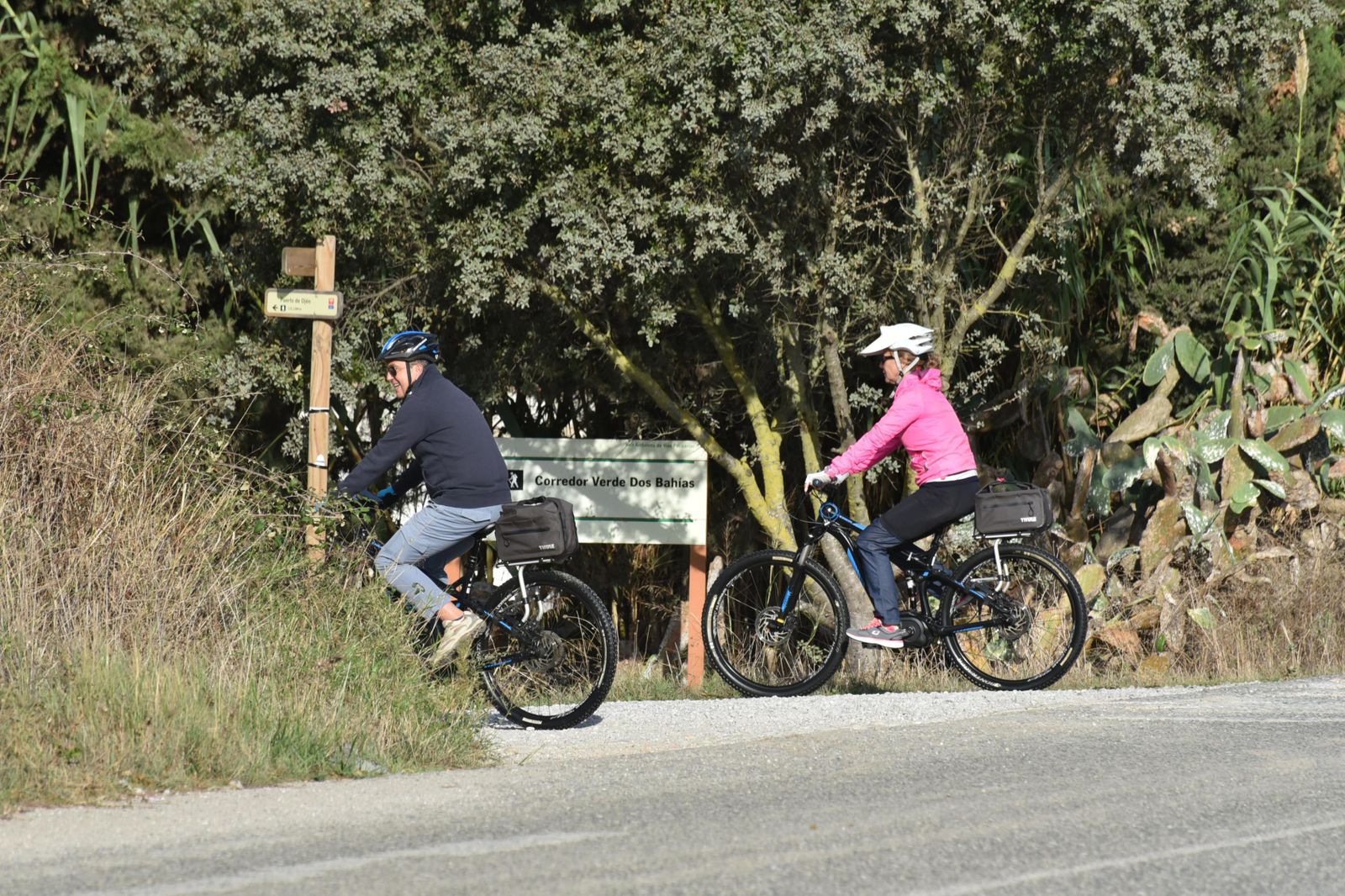 Dos personas acceden en bicicleta a la pista del Corredor Verde Dos Bahías desde las inmediaciones de la Venta el Frenazo, en Los Barrios.
