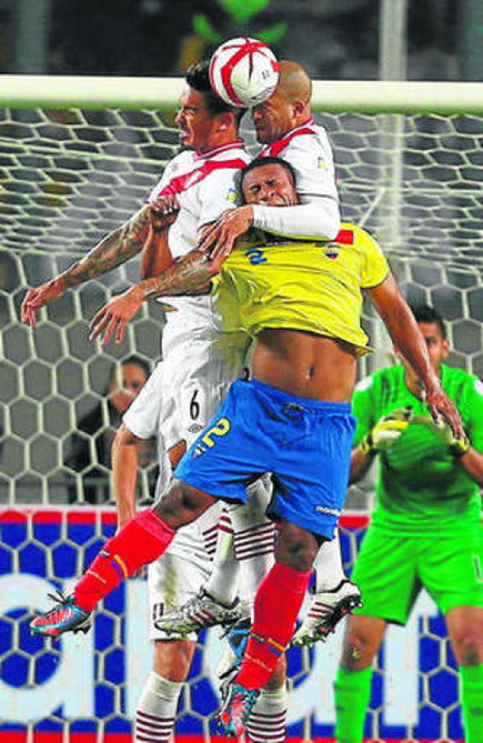 El ecuatoriano Jorge Guagua disputa un balón con dos jugadores peruanos.