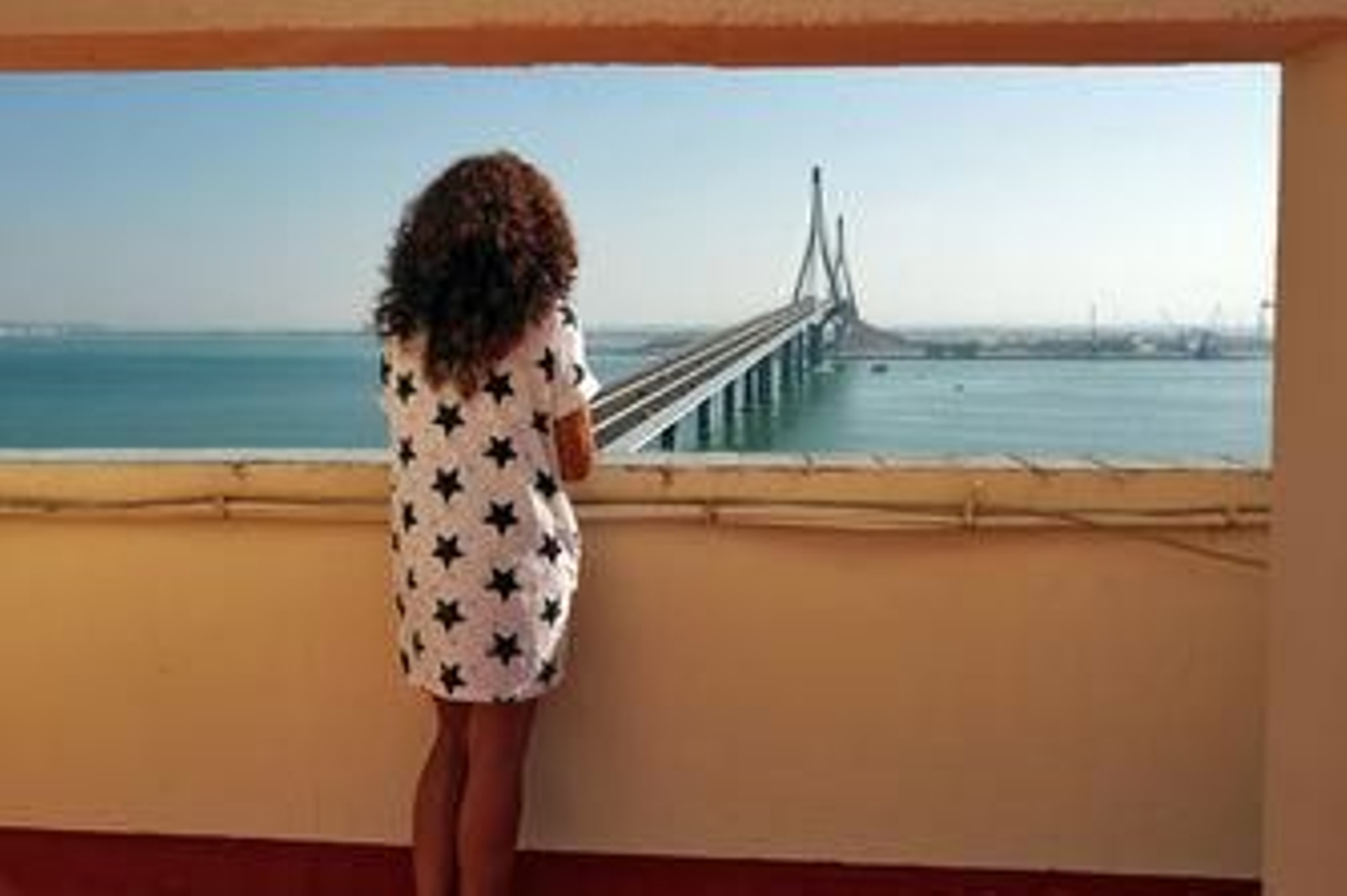 Una vecina observa el puente de la Constitución desde la azotea de una finca.