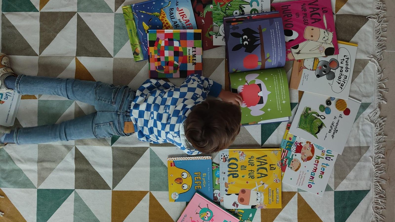 Un niño, rodeado de libros infantiles, lee el cuento 'El vampiro Edelmiro'