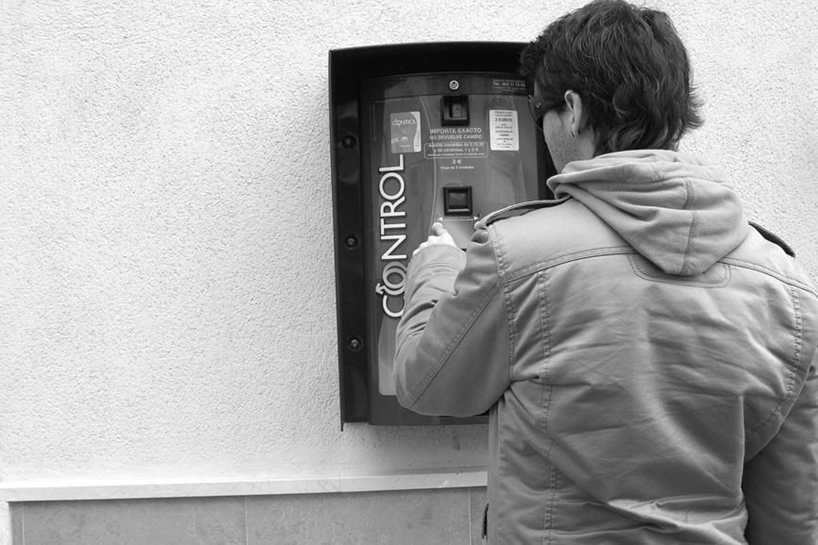 Imagen de archivo de un joven en una máquina de preservativos.