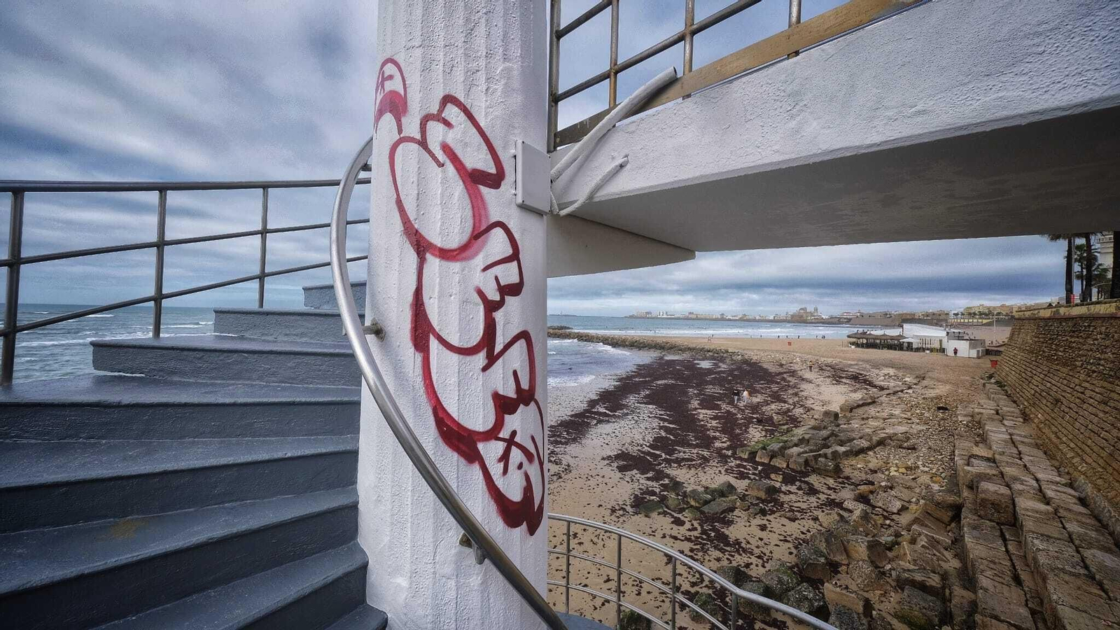 Una pintada en la columna de la escalera de caracol que da acceso a la playa frente a Asdrúbal.