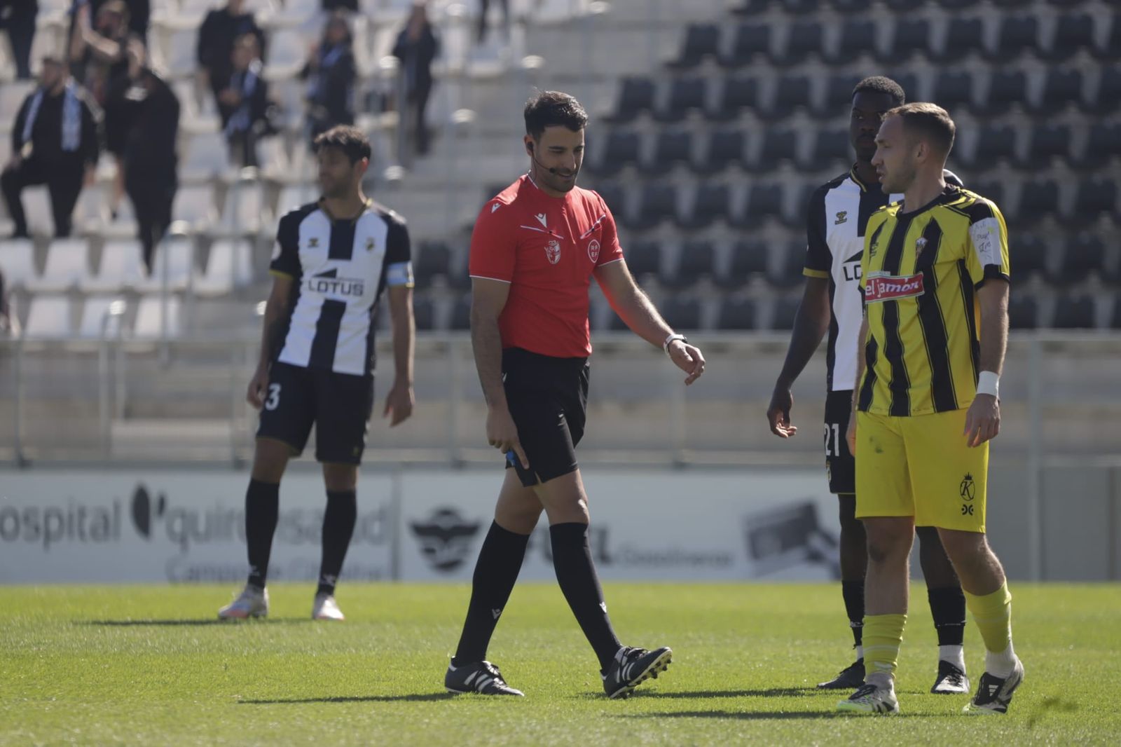 El árbitro sevilano Carlos Hidalgo se señala el gemelo cuando detiene el partido para ser atendido